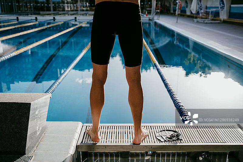 年轻的男性游泳运动员站在泳池边图片素材