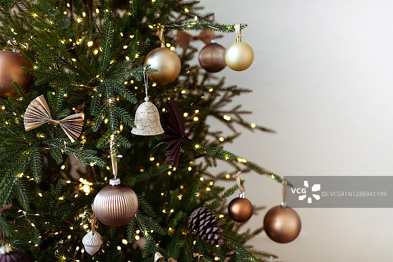 彩色棕色球和白色背景上的装饰品的节日装饰圣诞树的特写。图片素材