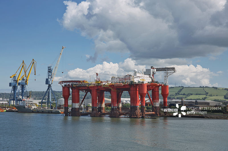 大型工业起重机在爱尔兰贝尔法斯特港装载集装箱船图片素材