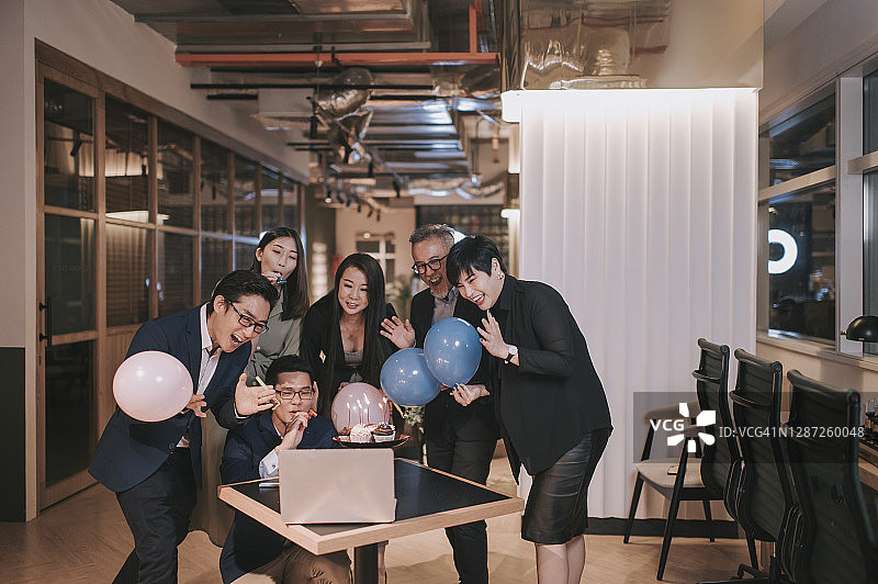 一群亚洲华人同事在看手提电脑视频会议，和同事庆祝生日图片素材