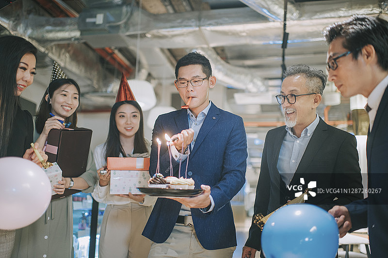 亚洲华人商人点燃生日蜡烛惊喜办公室生日派对庆祝图片素材