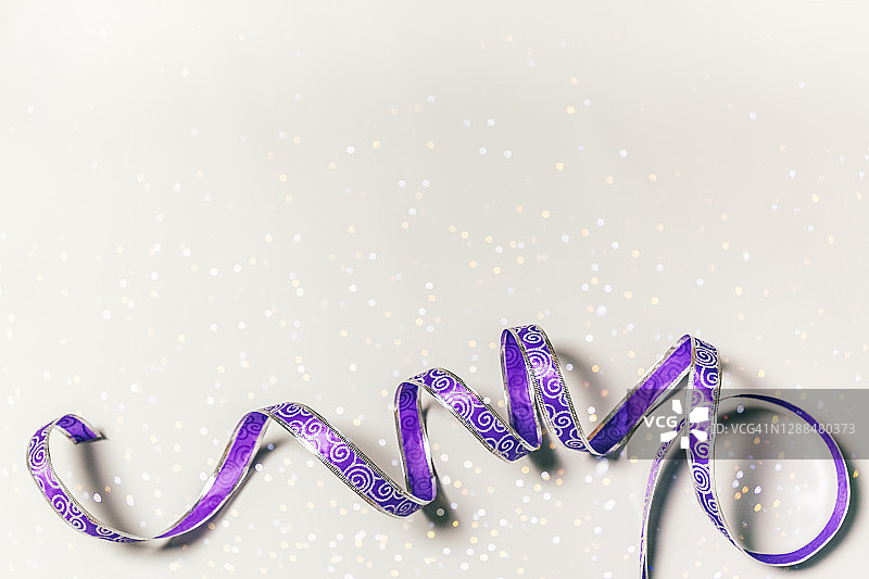 背景与圣诞灯和花哨闪亮的礼物丝带。副本的空间。丁香紫色的颜色。图片素材
