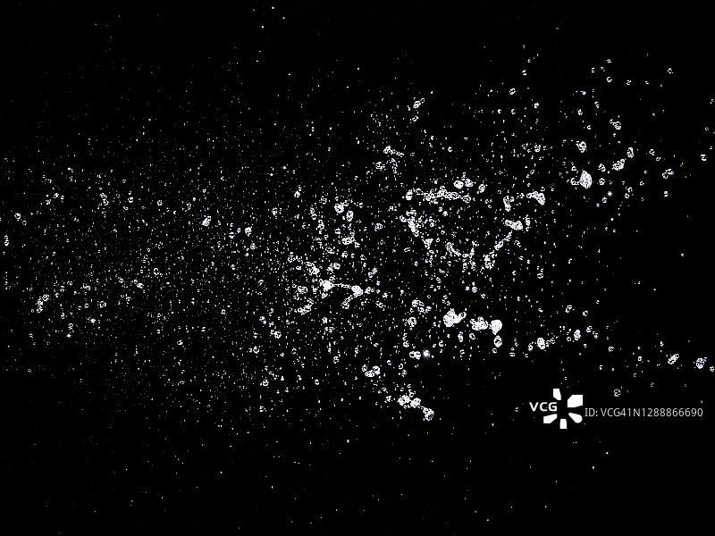 飞溅、喷射和水滴在运动中悬浮在空中的黑色背景。图片素材