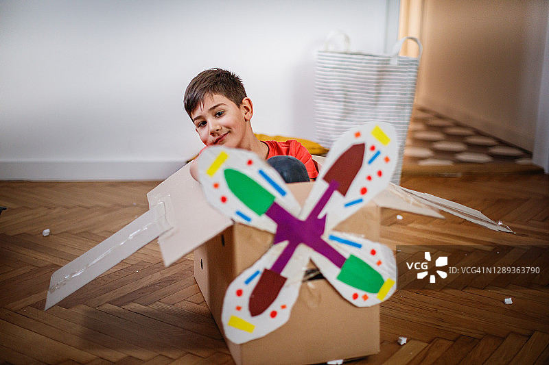 男孩坐在纸板做的假飞机里图片素材