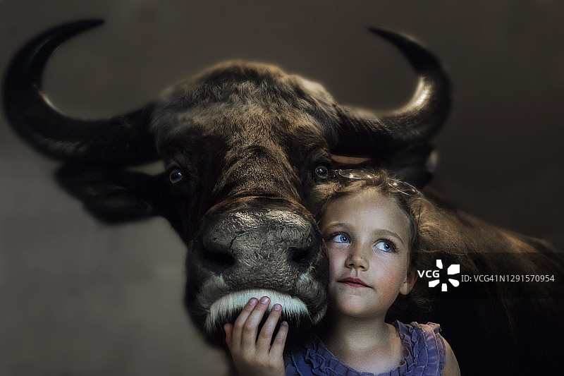 一个微笑的女孩和一头牛站在一起的肖像图片素材