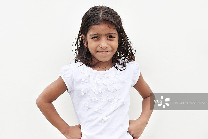 6-7岁可爱小女孩的肖像，靠在白色的墙壁上图片素材
