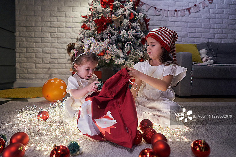 好奇的姐妹们，探索着大圣诞袜，无法掩饰收到礼物时的兴奋图片素材