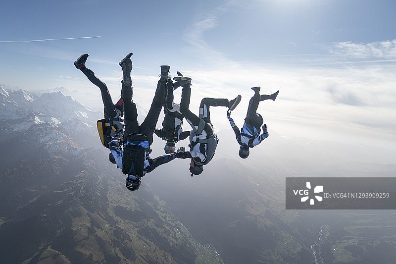 自由落体跳伞者在半空中飞过山脉和山谷图片素材