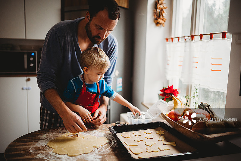 爸爸和儿子穿着睡衣在家里的厨房里烤圣诞饼干图片素材