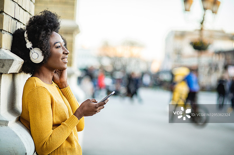 非裔美国妇女在户外戴着耳机听音乐图片素材