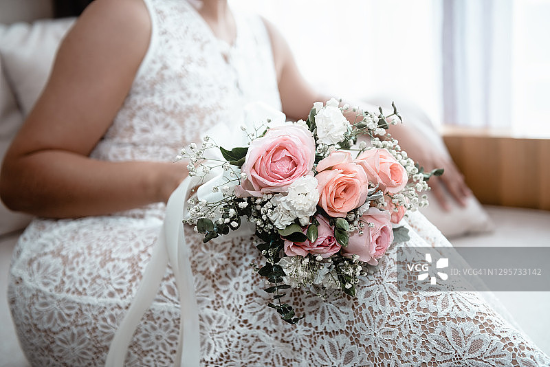 泰国新娘的特写婚纱是拿着鲜花捧花，而等待在婚礼房间。图片素材