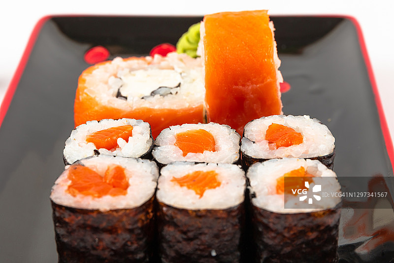 新鲜的费城卷鲑鱼和软奶酪在黑红色的盘子在白色的背景图片素材