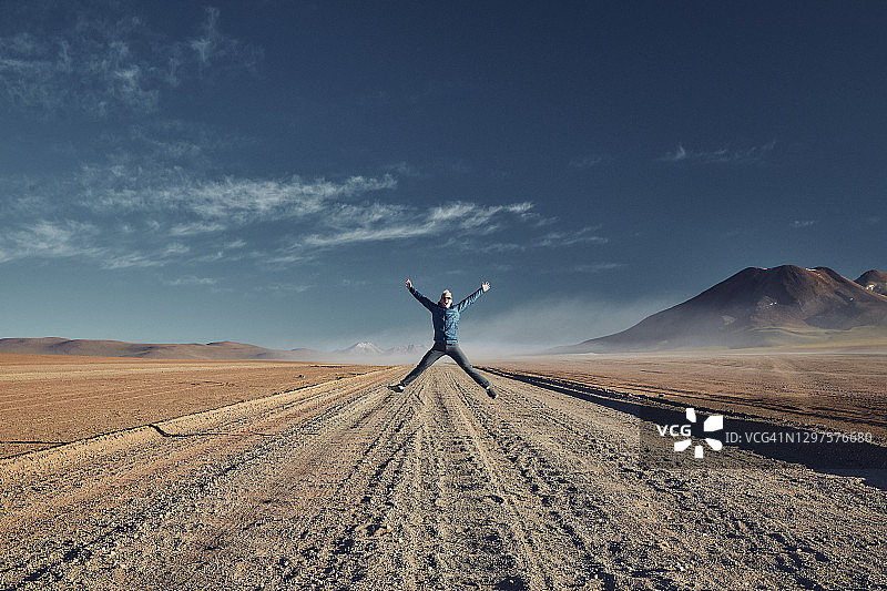 年轻的男旅游明星兴奋地跳在阿塔卡马沙漠图片素材