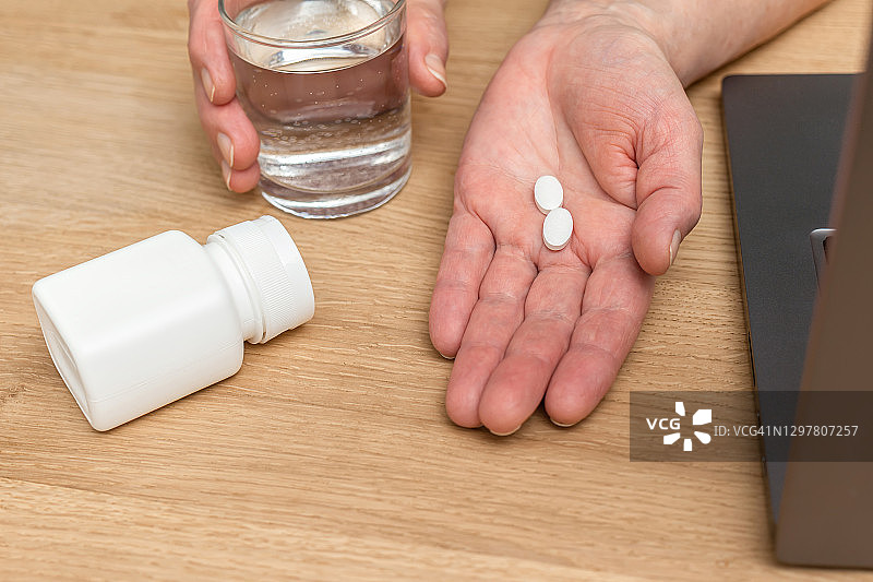 白色止痛片或抗生素用于治疗老年妇女的手掌心，玻璃与水，药品和维生素补充剂的概念，近景图片素材