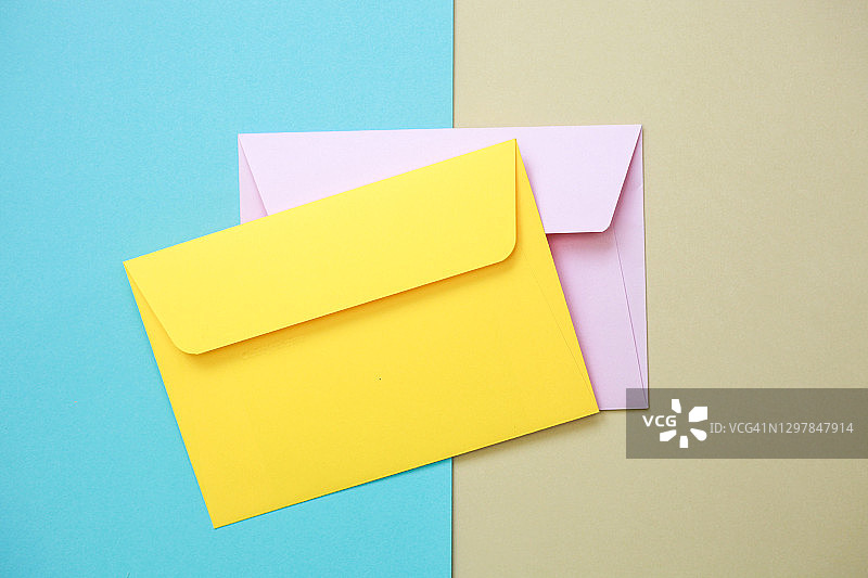 黄色和粉红色的纸信封在蓝色和黄色的背景图片素材