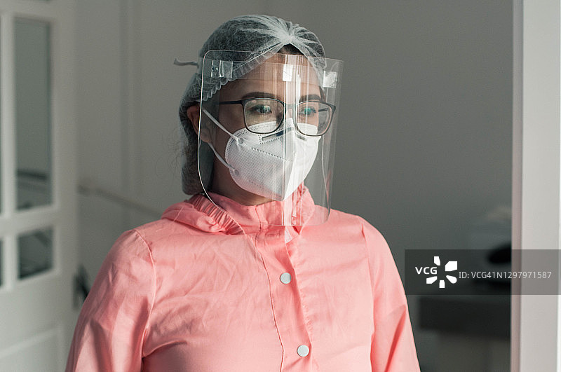 一幅东南亚女医生身穿防护服、面罩和面罩在诊所的肖像图片素材