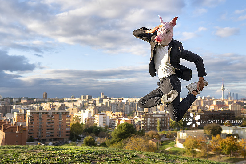 戴着猪面具的商人在城市的山上跳伞图片素材