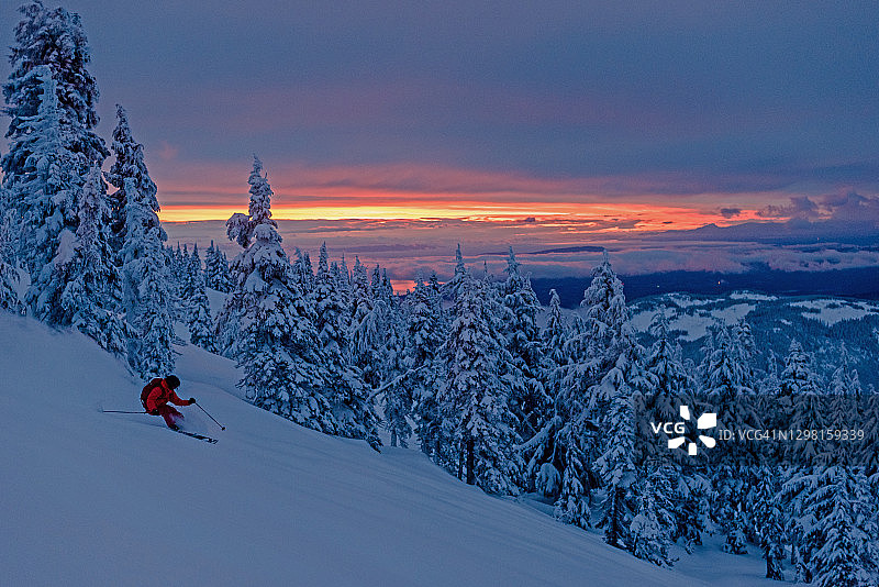 黎明时分，一个偏远地区的滑雪者从陡峭的粉斜坡上下来图片素材