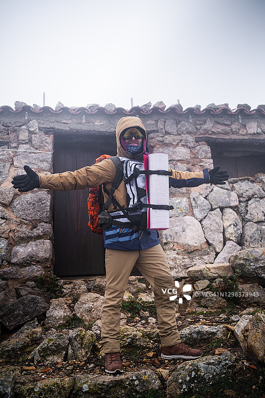 一个人在山上的避难所前举起双手图片素材