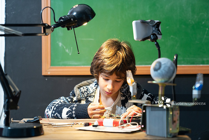 一个小学生在绿色黑板前研究机器人和编程图片素材