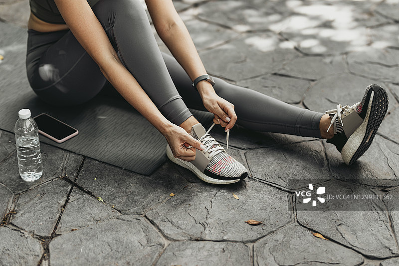 在运动鞋上系鞋带的匿名健康女人图片素材