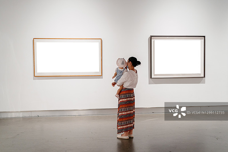 亚洲妇女和她的孩子在画廊观看展览图片素材