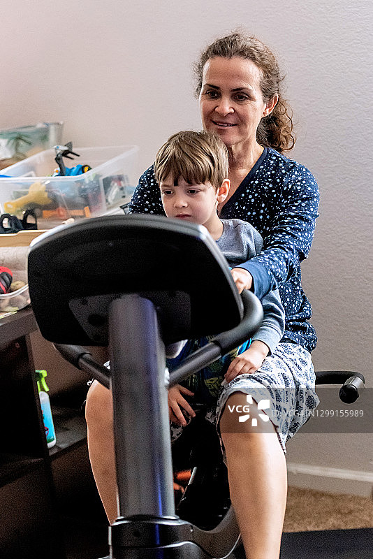 成熟的女人坐在自行车上锻炼抱着她的儿子图片素材