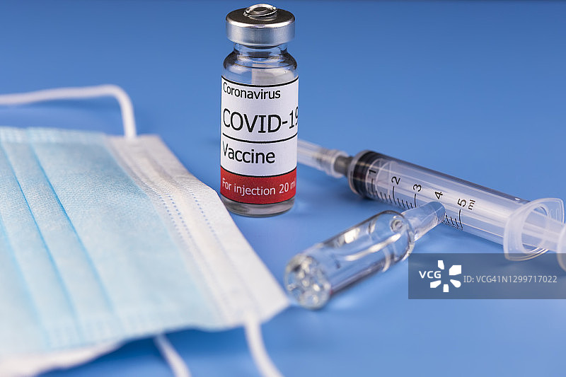 蓝色背景注射疫苗。冠状病毒疫苗,COVID-19。全球大流行。图片素材