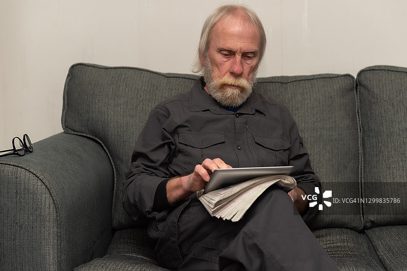 一个退休男子坐在家里使用平板电脑图片素材