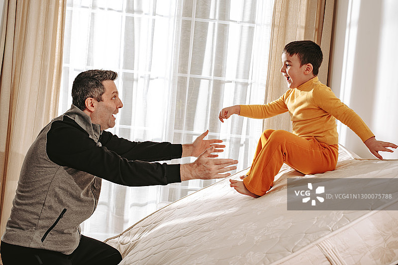 父亲和小儿子在床上玩滑梯图片素材