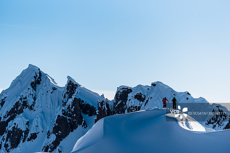 滑雪登山运动员攀登高耸的山脉下面的山脊线图片素材