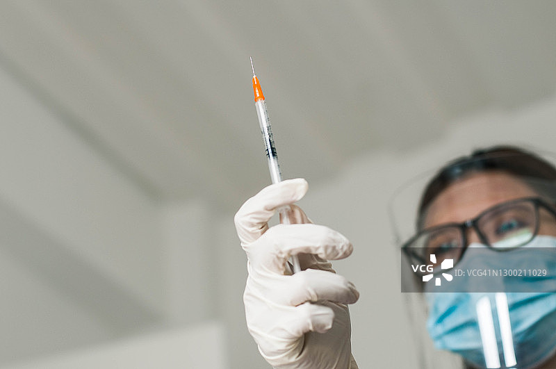 一名年轻的东南亚女医生正拿着冠状病毒疫苗注射针图片素材