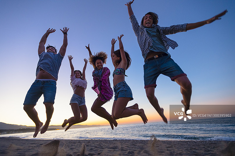 一群朋友在海滩上欢蹦乱跳。图片素材
