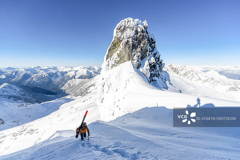 滑雪登山运动员登上山顶斜坡，山下有山图片素材