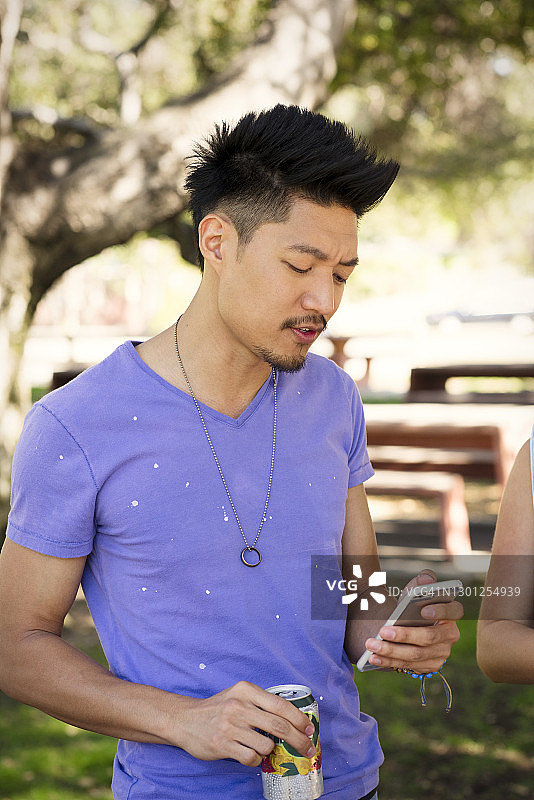 一名男子在公园边拿着饮水机边用智能手机图片素材