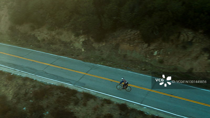 鸟瞰骑自行车者在山路上快速骑行图片素材