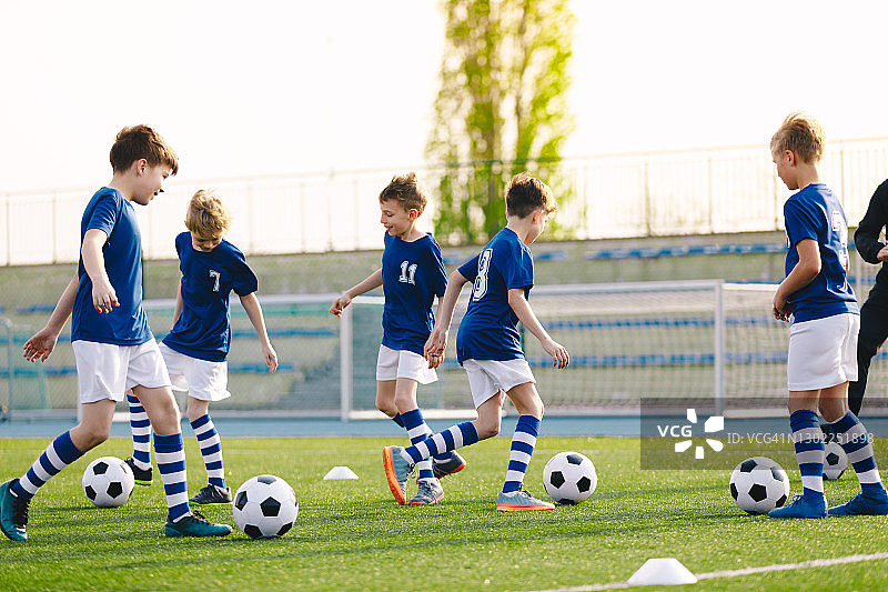 儿童足球教育。儿童体育。训练单位足球队的年轻教练和孩子们。青年队教练训练学校的男孩在足球图片素材