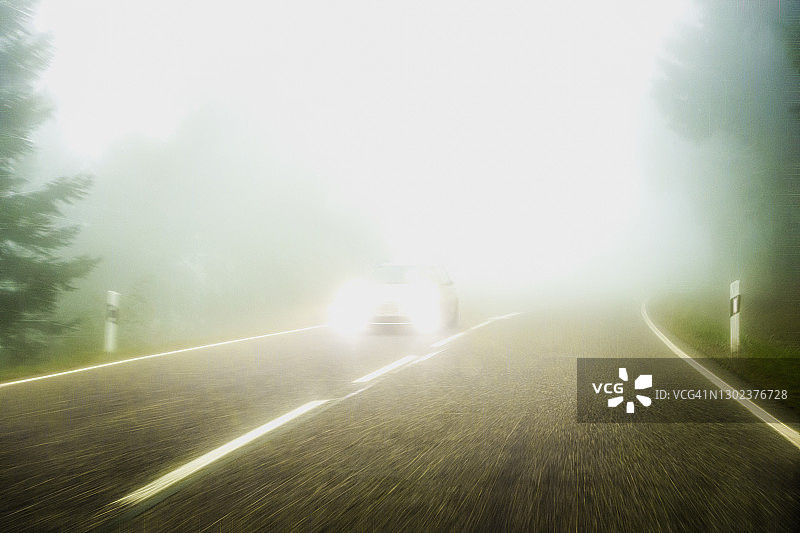 在雾中开车，有辆车驶近图片素材