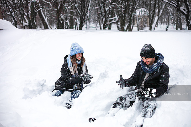 快乐的年轻夫妇男人和女人拥抱和有乐趣的户外在冬天在下雪的天气图片素材