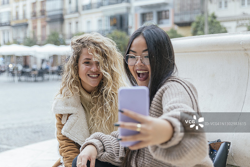 开心的女性朋友用智能手机自拍图片素材