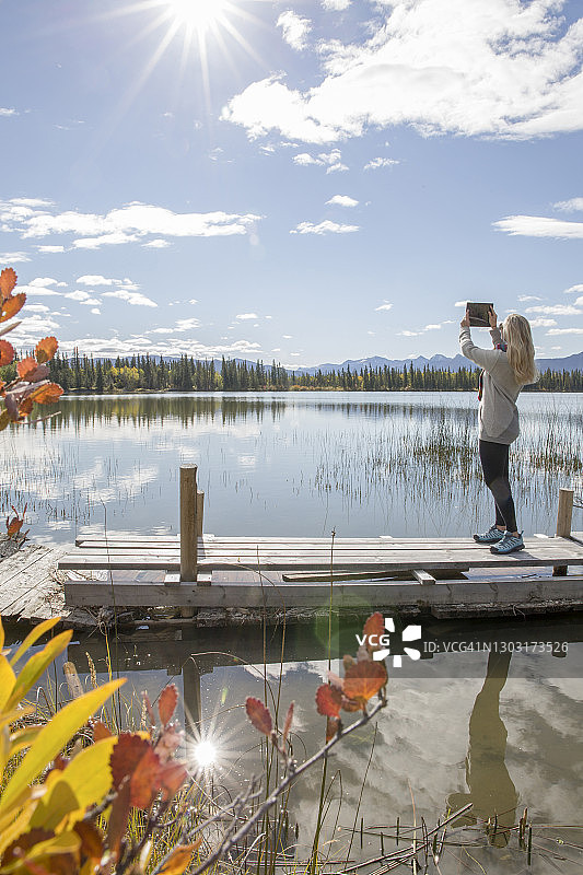 清晨，一名女子在高山湖边用平板电脑拍照图片素材
