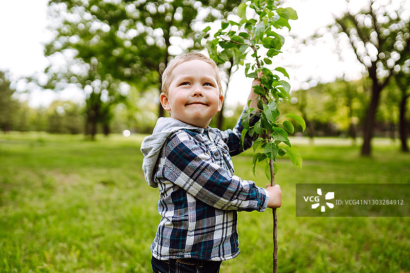 可爱的孩子在黑土上种小树。有趣的小园丁。春天理念，关爱自然。图片素材