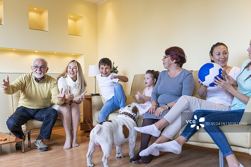 兴奋的多代同堂的家庭正在享受一场足球比赛在家。图片素材