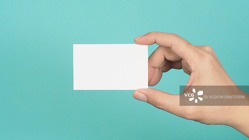 男性手持白色空白卡片孤立在绿色或蒂芙尼蓝色背景上。图片素材