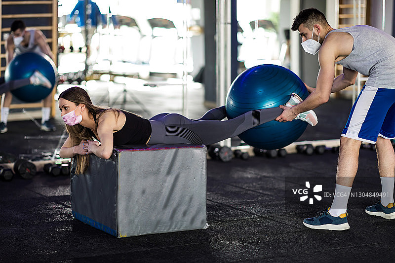 一名女子在教练的帮助下在健身房锻炼图片素材