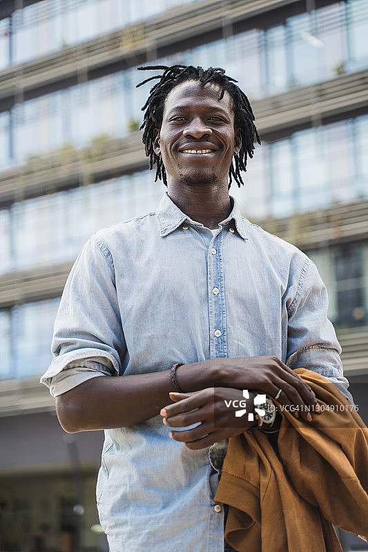 优雅快乐的年轻黑人企业家穿着一件蓝色衬衫在一个办公商业区图片素材
