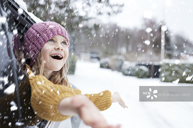 快乐的女孩透过车窗享受雪花图片素材