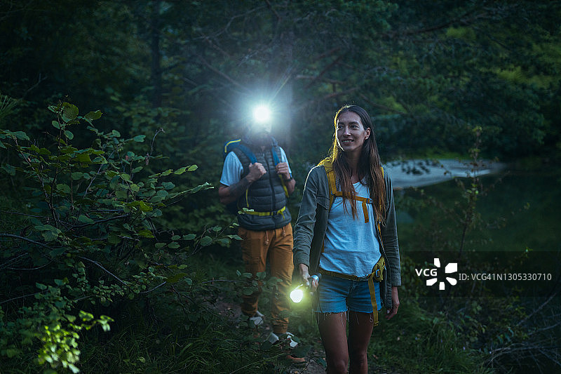 带着手电筒在树林里散步的徒步旅行者图片素材
