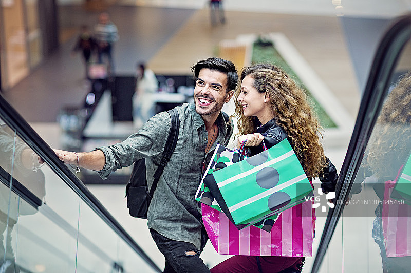一对购物情侣正站在商场的自动扶梯上图片素材