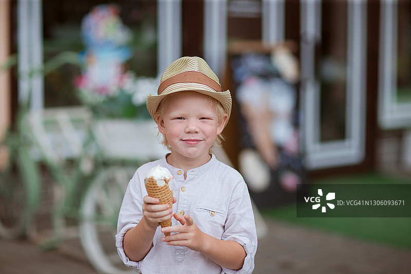 一个戴着帽子的金发男孩正在试他的冰淇淋汤照片。图片素材